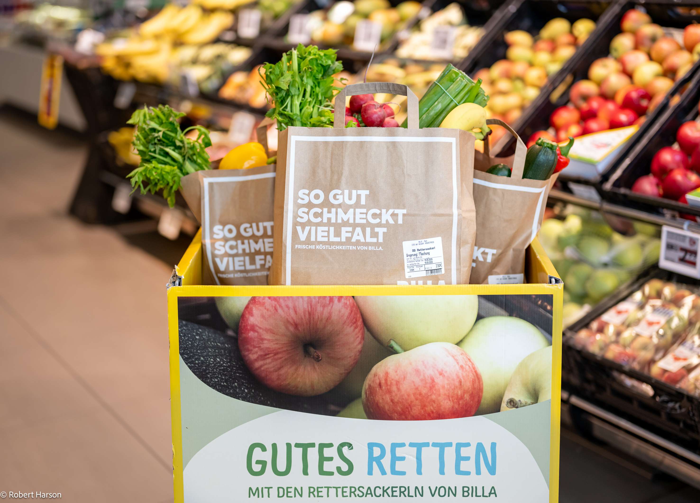 Several paper bags containing fresh fruit and vegetables are sitting in a yellow bin labelled &lsquo;Gutes Retten&rsquo; in a supermarket.